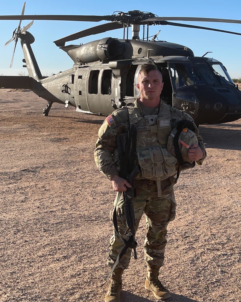 Josh in combat uniform in front of a Black Hawk